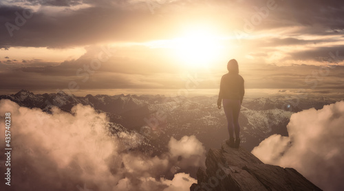 Fantasy Adventure Composite with a Girl on top of a Mountain Cliff with Dramatic Landscape in Background. Landscape from British Columbia, Canada. Dramatic Stormy Sunset Sky.