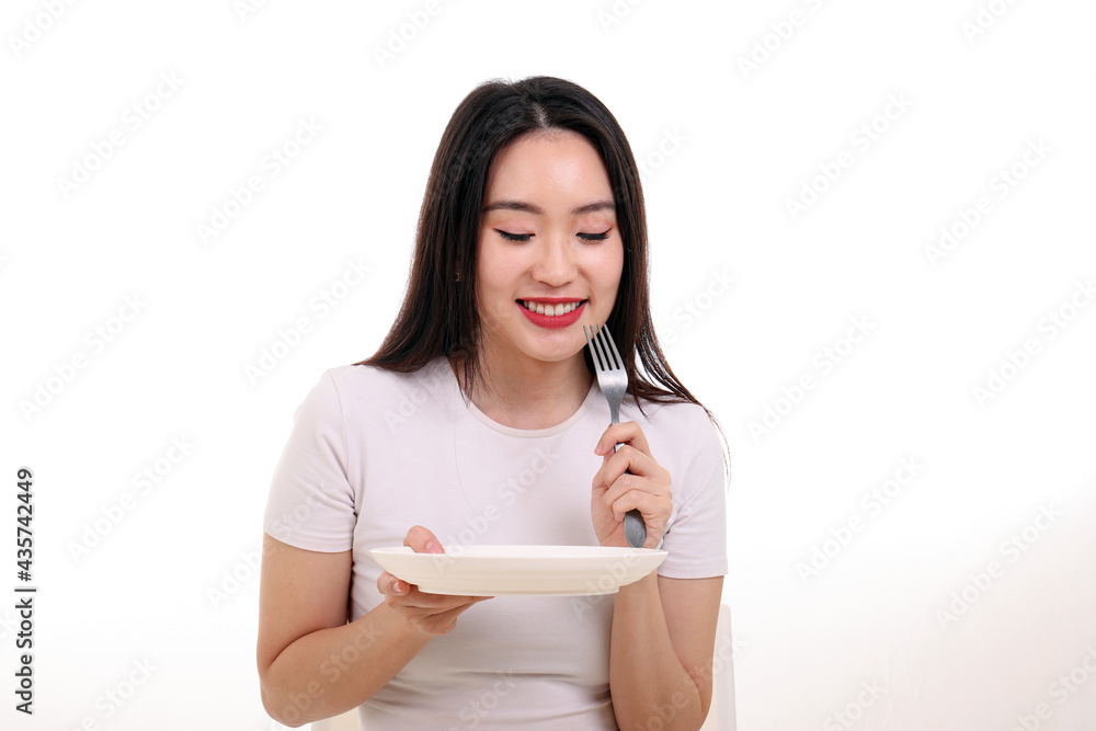 Beautiful young south east Asian woman pretend acting posing holding empty fork spoon white plate in hand eat taste look see white background Beautiful young south east Asian woman pretend acting posing holding empty fork spoon white plate in hand eat taste look see white background