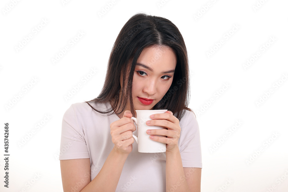 Beautiful young south east Asian woman holding white coffee tea cup emotion expression on white background look down Beautiful young south east Asian woman holding white coffee tea cup emotion expression on white background look down