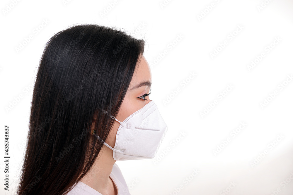 Beautiful young south east Asian woman wearing N95 anti virus bacterial surgical face mask on white background side view Beautiful young south east Asian woman wearing N95 anti virus bacterial surgical face mask on white background side view