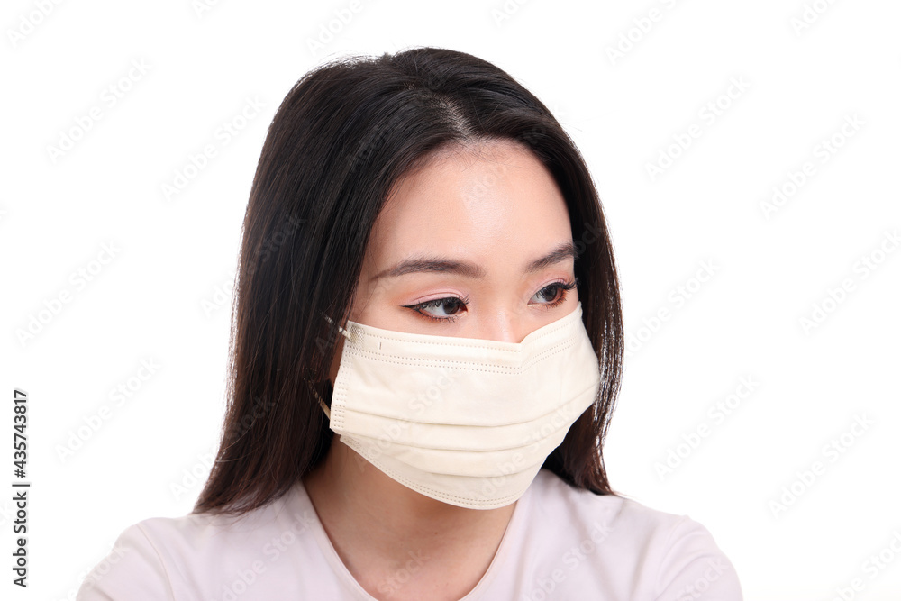 Beautiful young south east Asian woman wearing yellow off white three ply anti virus surgical face mask on white background look left Beautiful young south east Asian woman wearing yellow off white three ply anti virus surgical face mask on white background look left