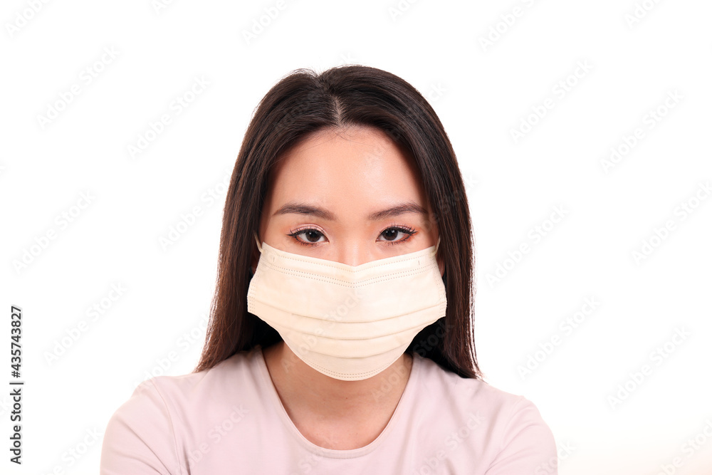 Beautiful young south east Asian woman wearing yellow off white three ply anti virus surgical face mask on white background look forward Beautiful young south east Asian woman wearing yellow off white three ply anti virus surgical face mask on white background look forward