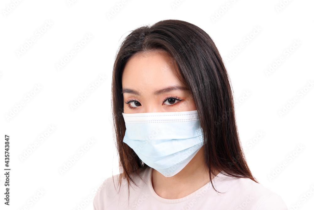 Beautiful young south east Asian woman wearing blue three ply anti virus surgical face mask on white background look forward Beautiful young south east Asian woman wearing blue three ply anti virus surgical face mask on white background look forward