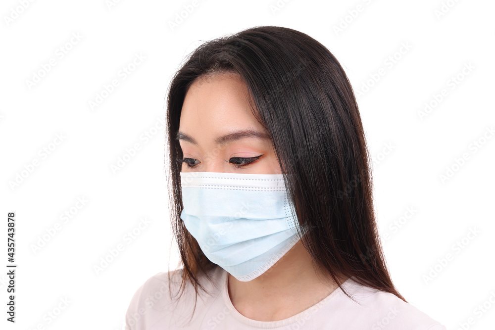 Beautiful young south east Asian woman wearing blue three ply anti virus surgical face mask on white background look down Beautiful young south east Asian woman wearing blue three ply anti virus surgical face mask on white background look down