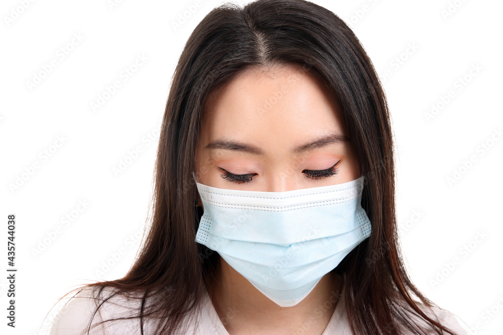 Beautiful young south east Asian woman wearing blue three ply anti virus surgical face mask on white background look down Beautiful young south east Asian woman wearing blue three ply anti virus surgical face mask on white background look down