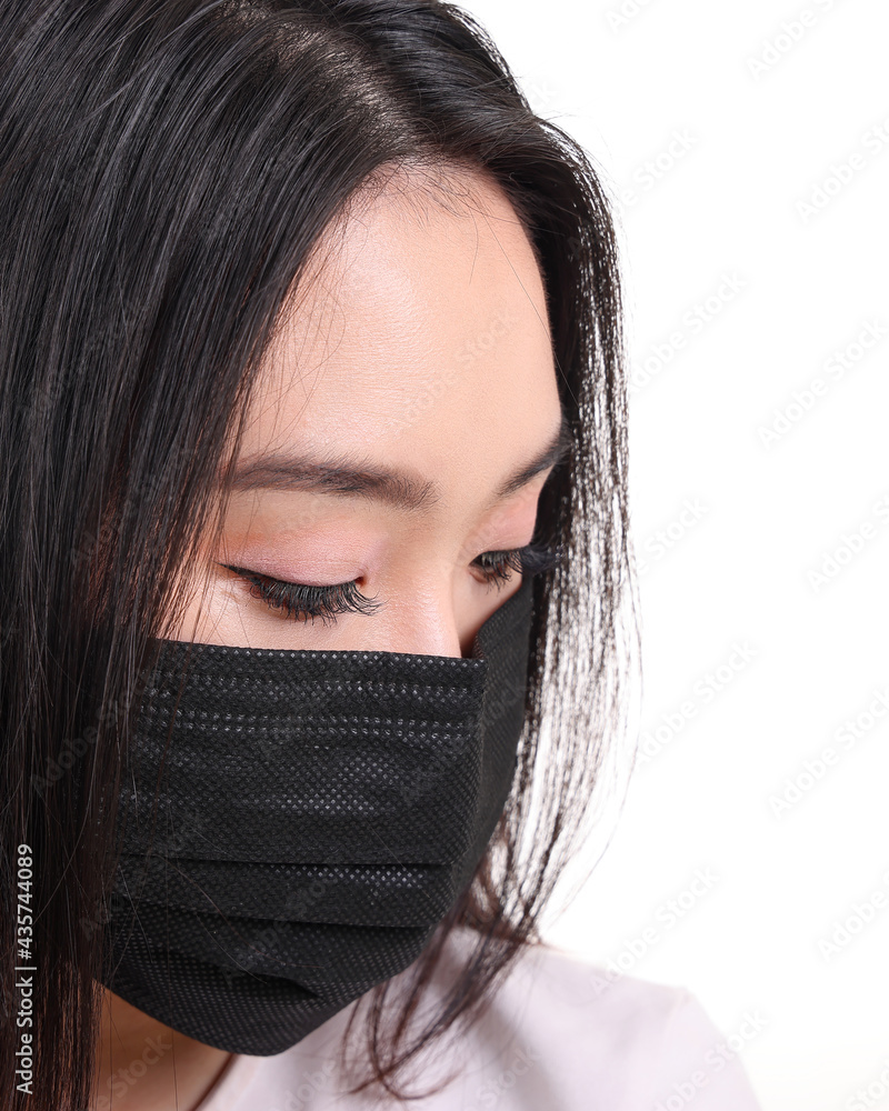 Beautiful young south east Asian woman wearing black three ply anti virus surgical face mask on white background look down Beautiful young south east Asian woman wearing black three ply anti virus surgical face mask on white background look down