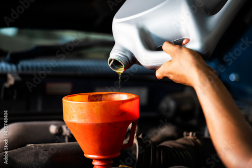 Old car oil change mechanic. Add new oil to the car. Pour fresh oil at the service station.