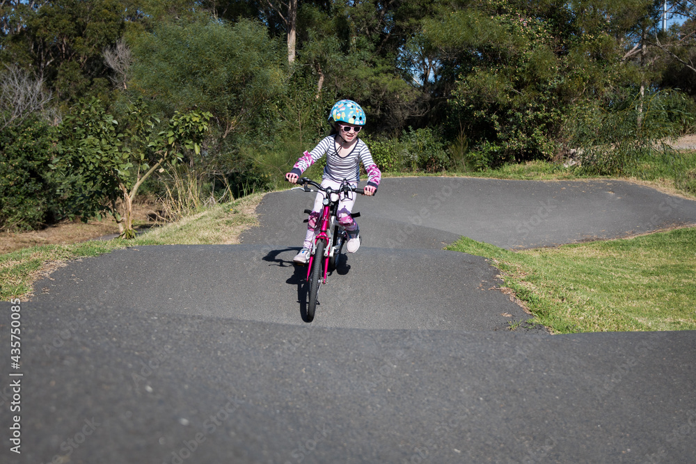 young caucasian girl riding push bike on pump track helmet fit outdoors active fun learn exercise bmx