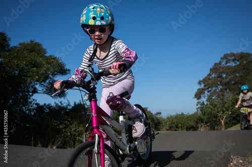 young caucasian girl riding push bike on pump track helmet fit outdoors active fun learn exercise bmx photo