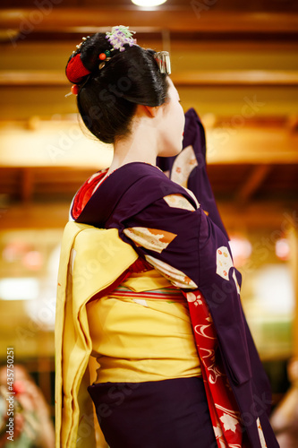 Maiko apprentice showing Japanese traditional dance. Maiko is an apprentice geisha. Maikos performing songs, playing shamisen or instruments for visitors on ozashiki. photo