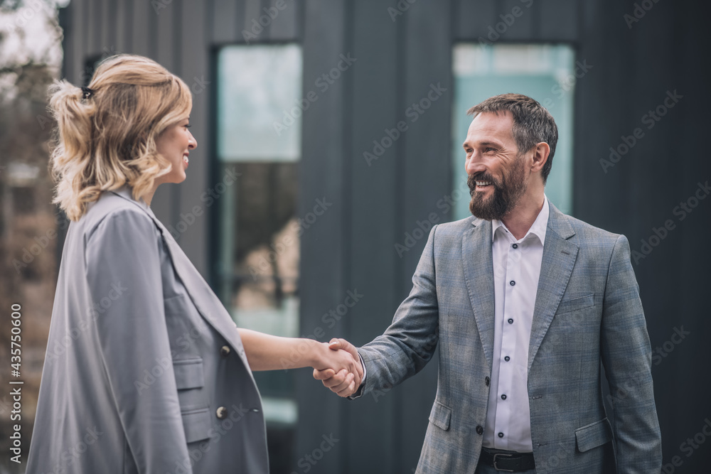 Joyful man and woman shaking hands with each other Joyful man and woman shaking hands with each other