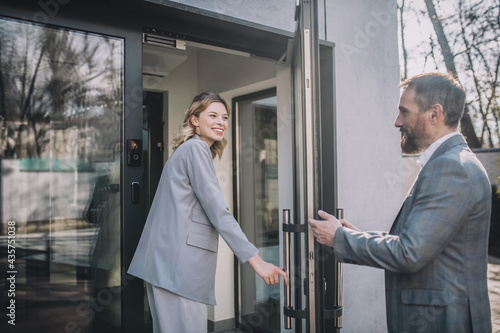 Konstfotografi Woman entering office and man opening door