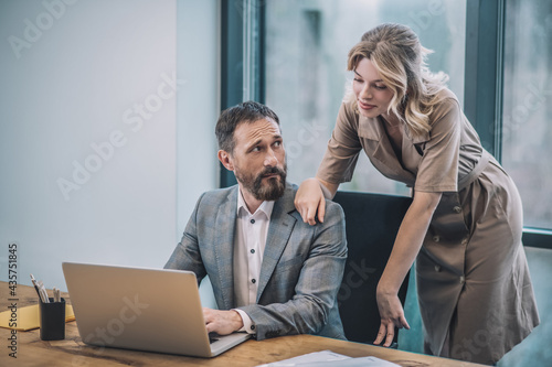 Man behind laptop woman touching his shoulder photo