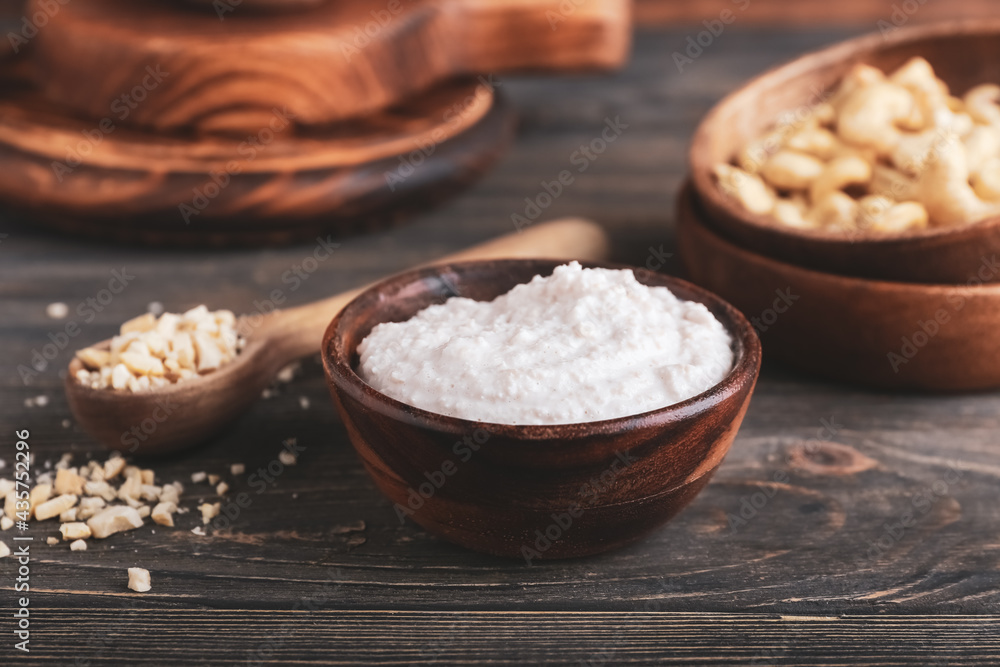 Bowl of sour cream with cashew nuts on dark wooden background Bowl of sour cream with cashew nuts on dark wooden background
