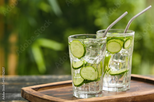 Glasses of cucumber lemonade on table outdoors
