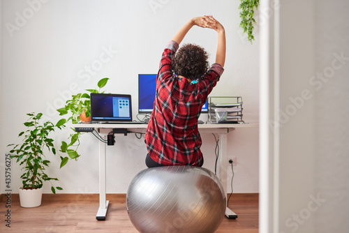 Woman stretches while working out sitting on a fitball