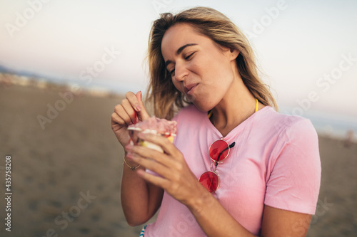 Woman eating ice cream outside on summer vacation in holiday beach resort.