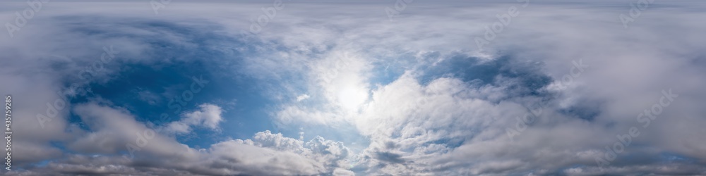 Obraz premium Blue evening sky seamless panorama spherical equirectangular 360 degree view with Cumulus clouds, setting sun. Full zenith for use in 3D graphics, game and aerial drone panoramas as sky replacement.