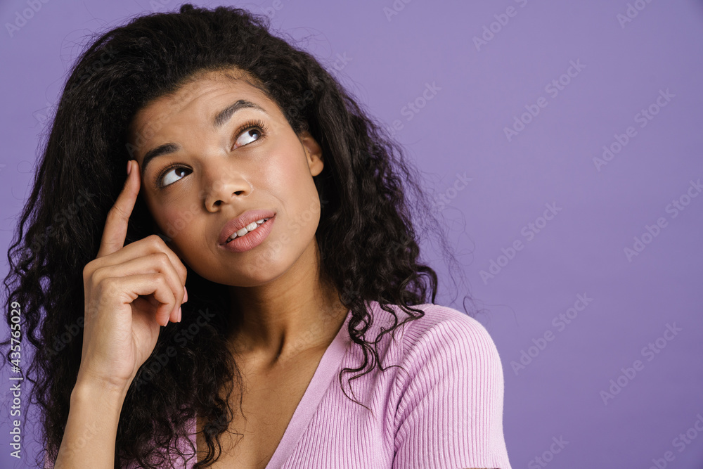 Young black woman with curly hair thinking and looking upward Young black woman with curly hair thinking and looking upward