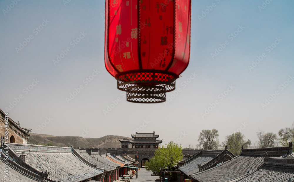 A red lantern above Chinese old house roof. The text on the lantern means 