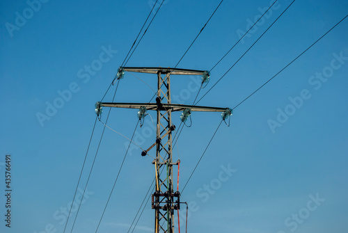 High voltage electric pole and transmission lines on clear blue sky background