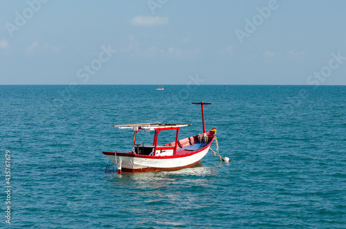 Small red boat in the water close to the beach