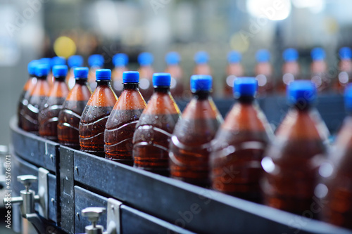 Plastic beer bottles on a conveyor belt in the background of a brewery