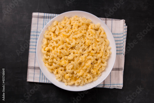 Macaroni and cheese on a white plate on a black background