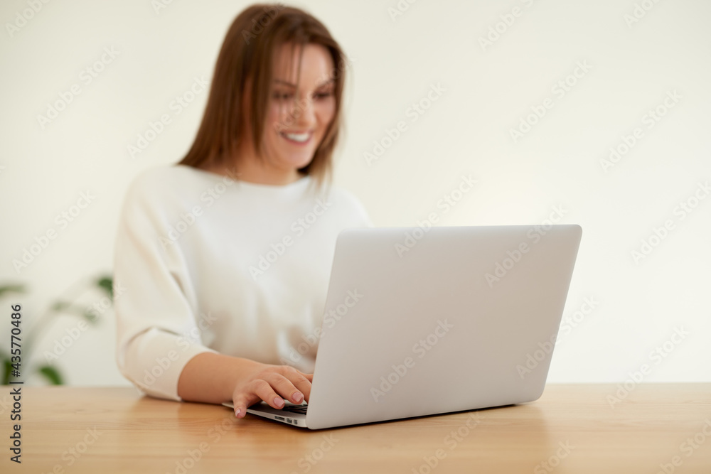 Smiling woman working on laptop at table Smiling woman working on laptop at table