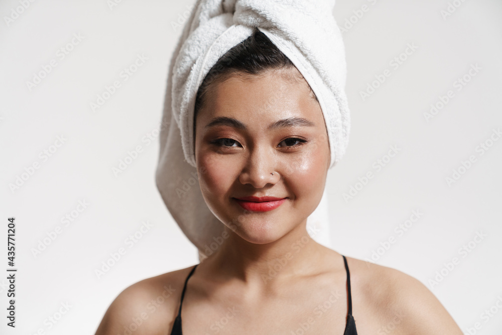 Brunette asian woman wearing swimsuit and towel smiling at camera Brunette asian woman wearing swimsuit and towel smiling at camera