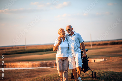 Senior golfers talking and walking on golf course. photo