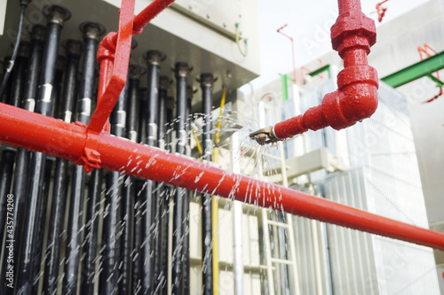 Water flowing from fire hose reel nozzles sprinkler system at Power transformer as part of the fire extinguishing system testing for safety in in part of an emergency in chemical plants.