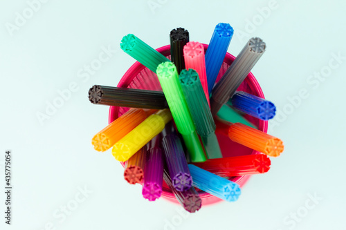 Set of multi-colored markers in a cup on white background. Top view.