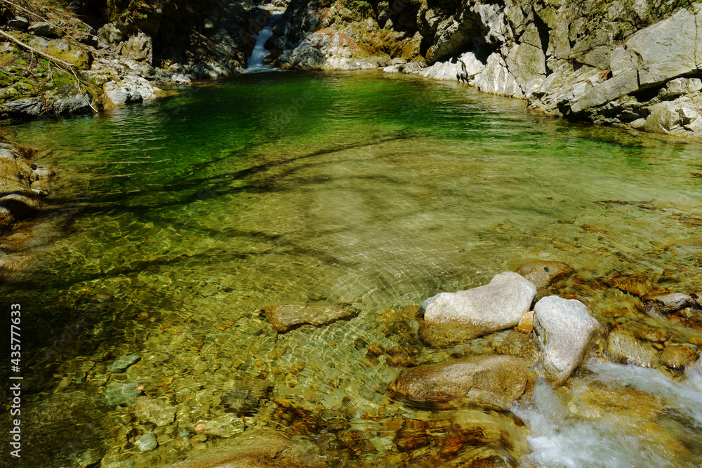 渓谷の川の縁の水がエメラルドグリーン色で美しい