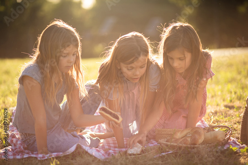 Three little girls having picnic in nature. photo