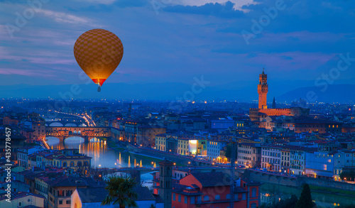 Hot air balloon flying over Cathedral Santa Maria del Fiore and Bridge of Ponte Vecchio on the river Arno at twilight blue hour - Florence, Italy
