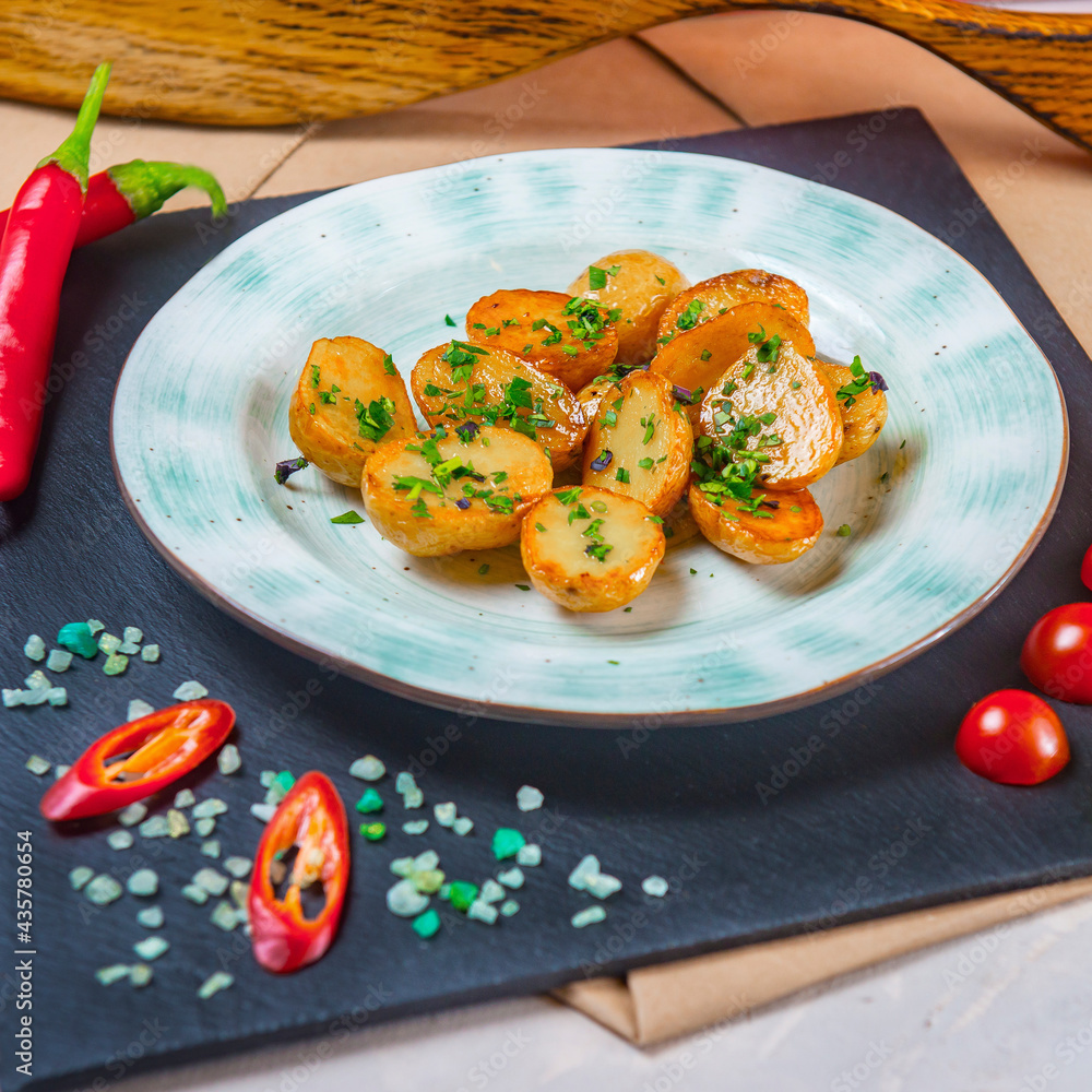 Country Style Fried Young Potato Halves On A Pale Blue Plate Which Stands On Black Stone Tray Country Style Fried Young Potato Halves On A Pale Blue Plate Which Stands On Black Stone Tray
