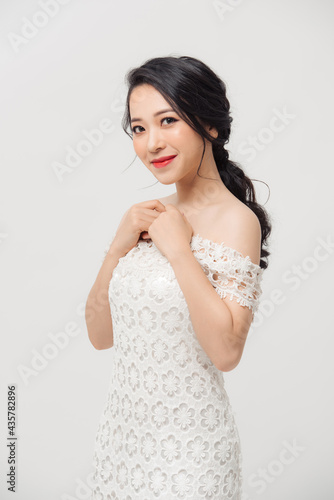 Beautiful Asian young woman in white dress posing on the white background. Beauty  fashion. Haircare. Cosmetics.
