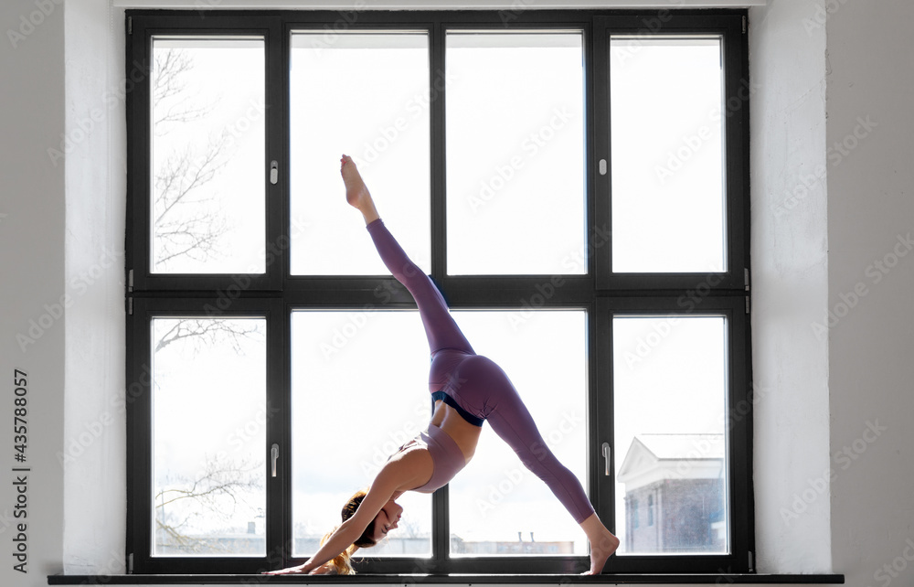 fitness, sport and healthy lifestyle concept - woman doing yoga exercise on window sill at studio