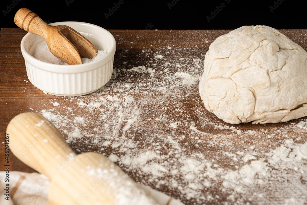 Top view of pizza dough, salt, rolling pin and kitchen cloth, on wooden table with flour, horizontal Top view of pizza dough, salt, rolling pin and kitchen cloth, on wooden table with flour, horizontal