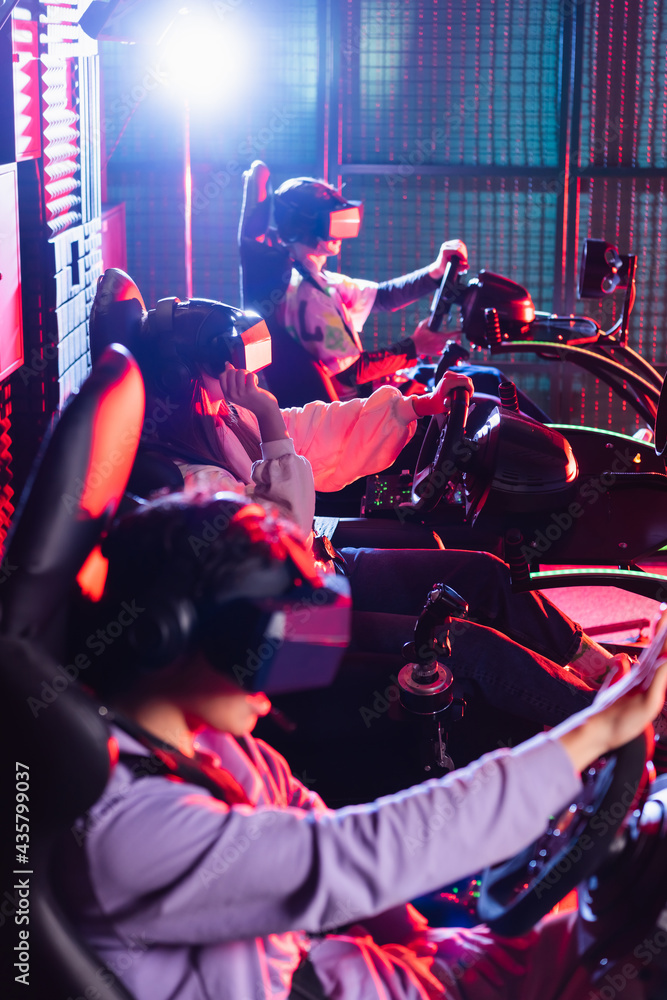 teenagers in vr headsets playing racing game in car simulators