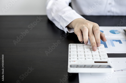 A woman pressing a white calculator is a financial expert checking company financial documents for the accuracy of the information before giving it to the executives. Concept of financial auditing.