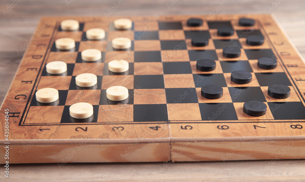 Checkers game on checkerboard in wooden background. Checkers game on checkerboard in wooden background.