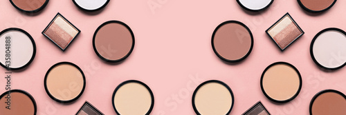 Makeup. Cosmetic products. Beige blush, eyeshadow and compact face powder on pink background. Banner. Tonal foundation. photo