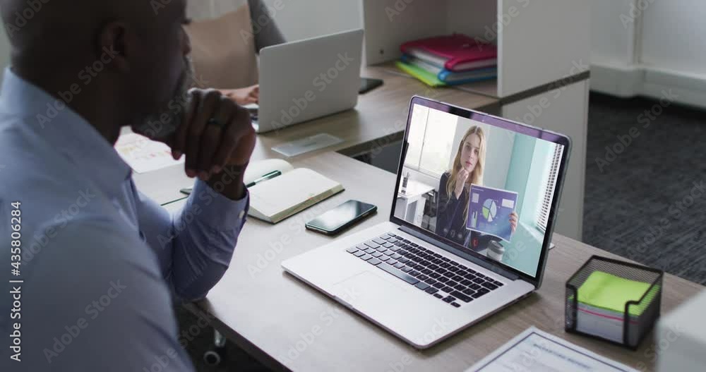 African american senior man having a video call with female colleague on laptop at office African american senior man having a video call with female colleague on laptop at office