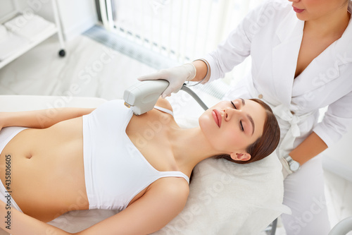 Obraz na płótnie Cosmetologist treating neck, decollete area and chest of woman with laser machin