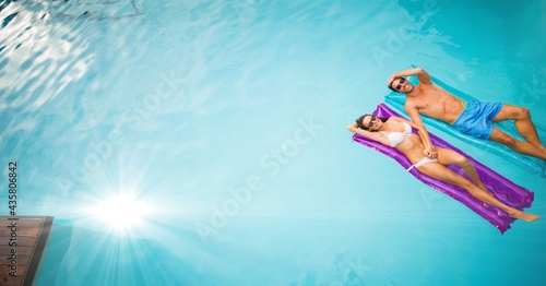 Composition of couple lying on inflatables in swimming pool with glowing light and copy space