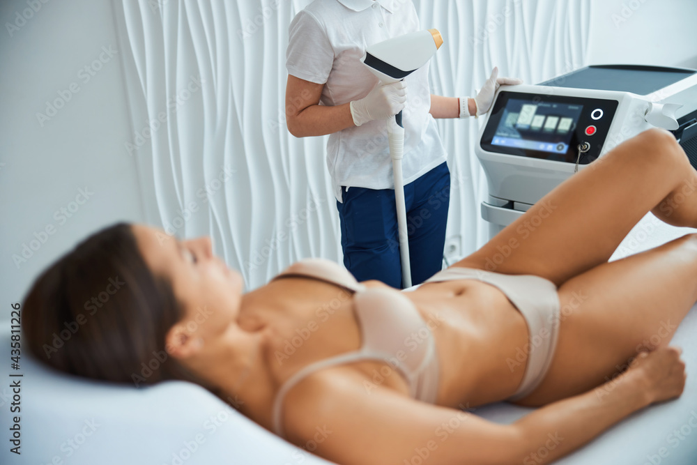 Qualified cosmetician preparing a young patient for a cosmetic procedure Qualified cosmetician preparing a young patient for a cosmetic procedure
