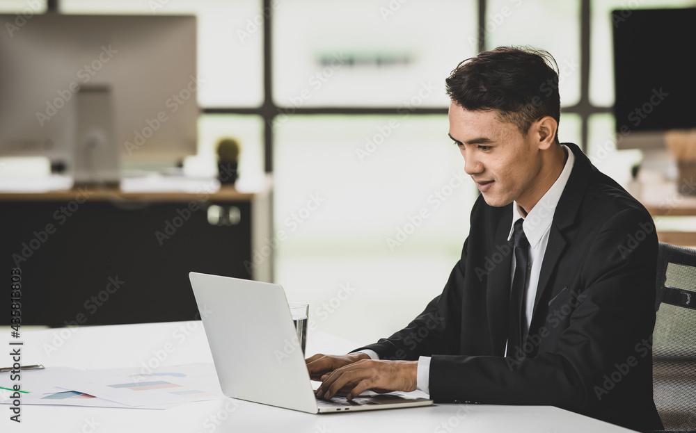 Cheerful businessman typing on laptop in office Cheerful businessman typing on laptop in office