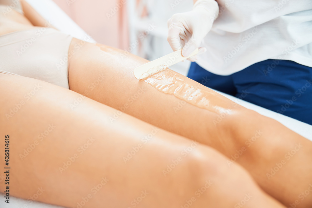 Dermatologist removing the excess gel from the female leg Dermatologist removing the excess gel from the female leg